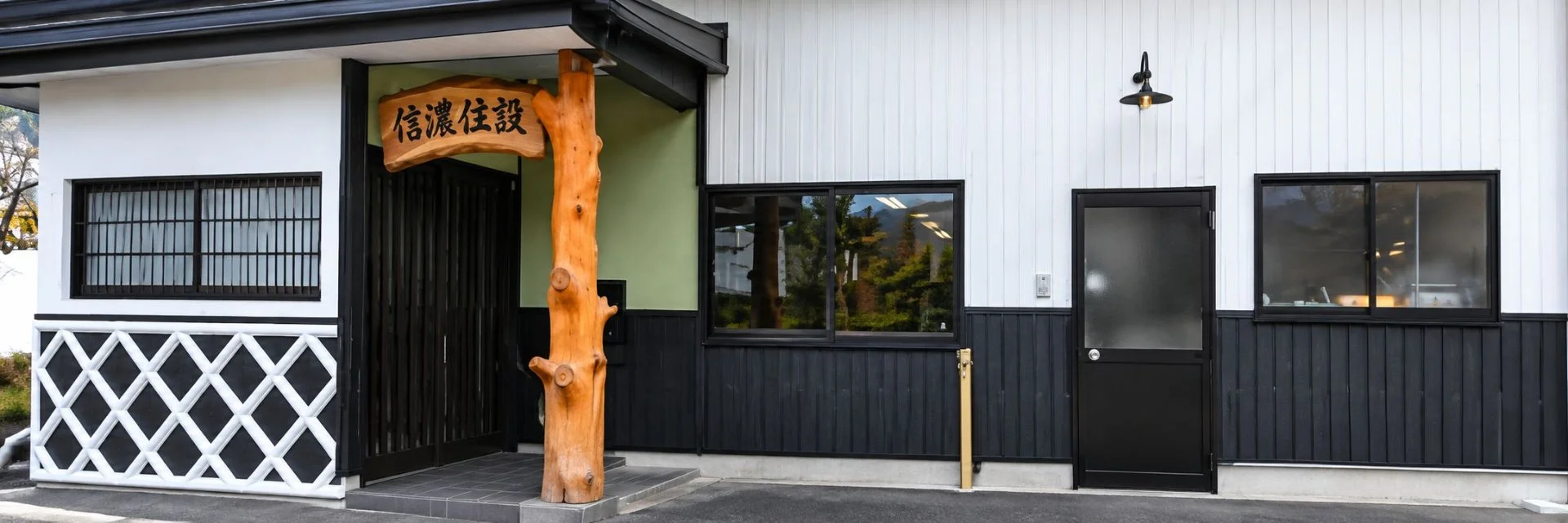 木製の看板と黒い板張りの外壁が並ぶ建物の外観